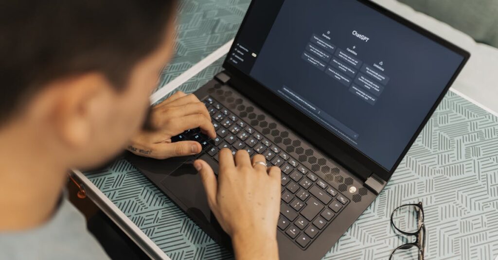 A man working on a laptop with AI software open on the screen, wearing eyeglasses.